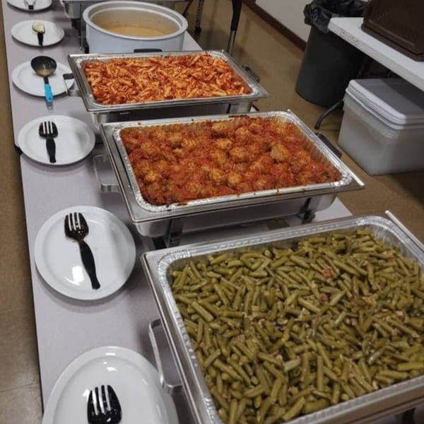 Buffet line with trays of pasta, meatballs, green beans, and a soup warmer.