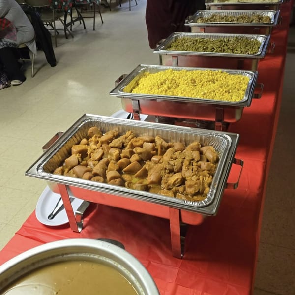 A buffet line with several chafing dishes filled with various foods like corn, green beans, and meat.